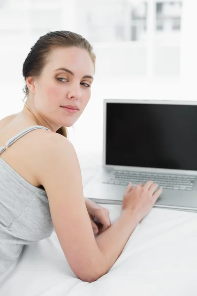 Thoughtful casual woman with laptop in bed — Stock Photo, Image