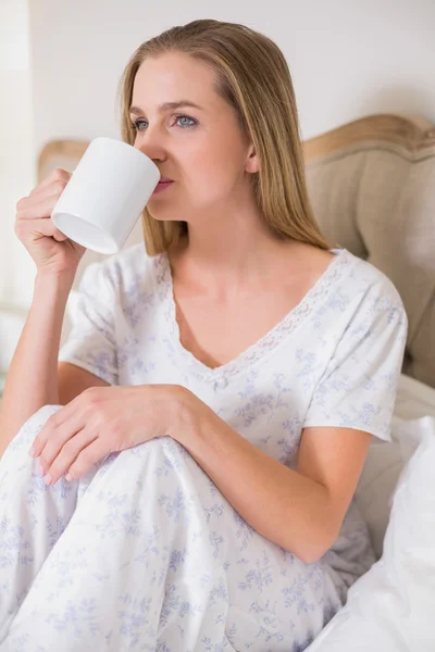 Natural calm woman sitting on bed drinking — Stock Photo, Image