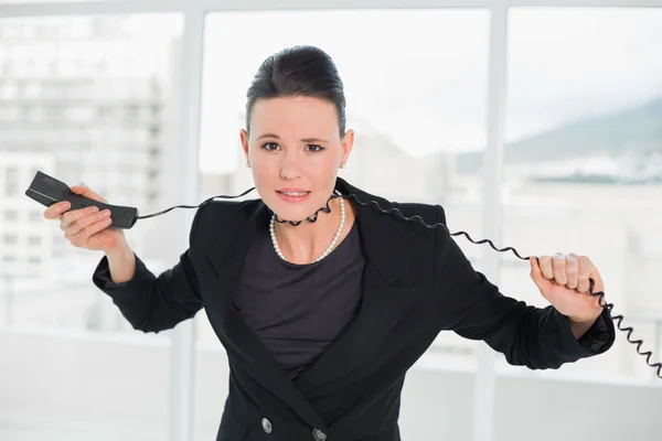 Frustrierte elegante Geschäftsfrau mit Telefonkabel um sich — Stockfoto