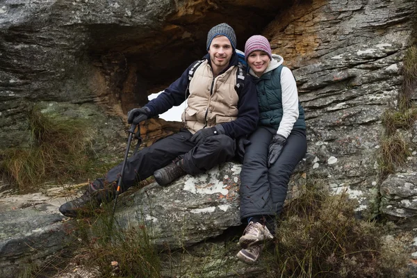 Smiling young couple sitting on rock while on a hike — Stock Photo, Image