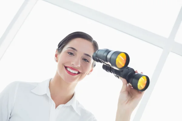 Mujer de negocios sonriente con prismáticos en la oficina — Foto de Stock