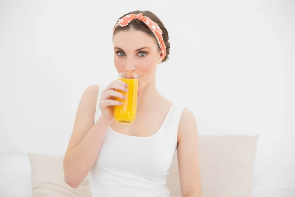 Frau trinkt ein Glas Orangensaft und blickt in die Kamera — Stockfoto