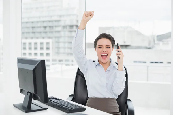 Элегантная и счастливая деловая женщина с помощью мобильного телефона в офисе — стоковое фото