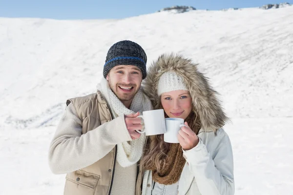 Couple in warm clothing with coffee cups on snowed landscape — Stock Photo, Image