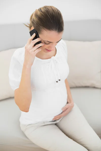 Ruhige schwangere Frau telefoniert, während sie ihren Bauch berührt — Stockfoto