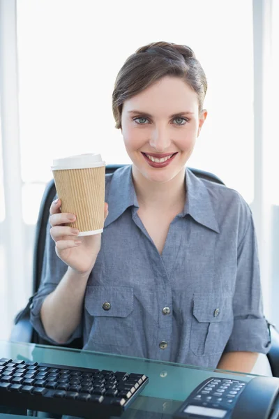 Cheerful young businesswoman presenting disposable cup — Stock Photo, Image