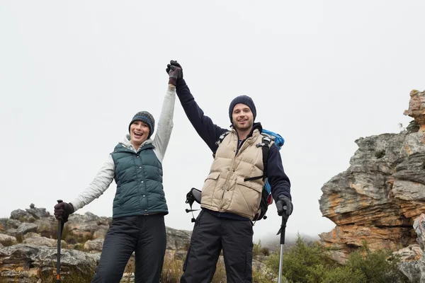 Couple on rocky landscape with hands raised against sky — Stock Photo, Image