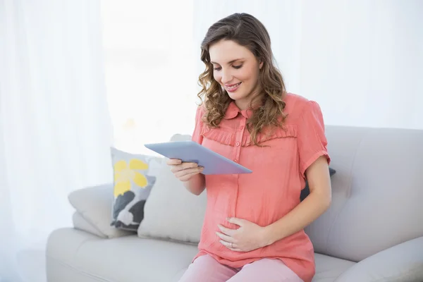 Zufriedene Schwangere hält ihr Tablet in der Hand — Stockfoto