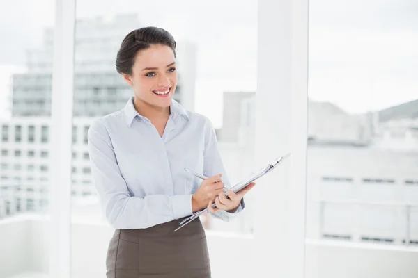 Femme d'affaires élégante et souriante avec presse-papiers au bureau — Photo