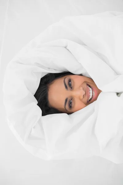 Mujer alegre acostada a cubierto en su cama — Foto de Stock