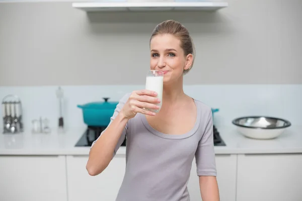 Lächelndes wunderschönes Model, das in die Kamera schaut und ein Glas Milch trinkt — Stockfoto