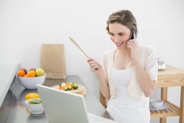 Conteúdo mulher telefonando com seu smartphone na cozinha — Fotografia de Stock