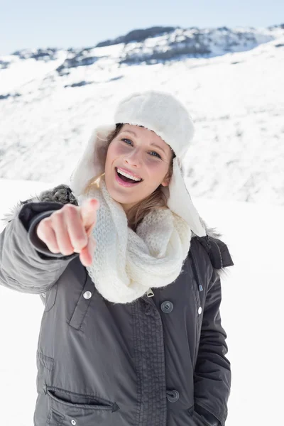 Femme en vêtements chauds pointant vers la caméra sur paysage recouvert de neige — Photo