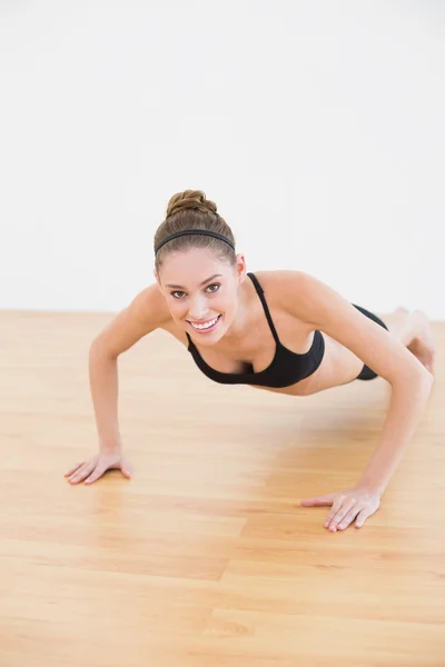 Adorável sorridente mulher vestindo sportswear fazendo press ups — Fotografia de Stock