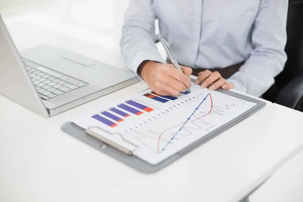Mid section of a businesswoman with graphs and laptop — Stock Photo, Image