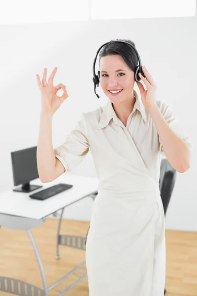 Geschäftsfrau trägt Kopfhörer, während sie im Büro mit Ok-Zeichen gestikuliert — Stockfoto