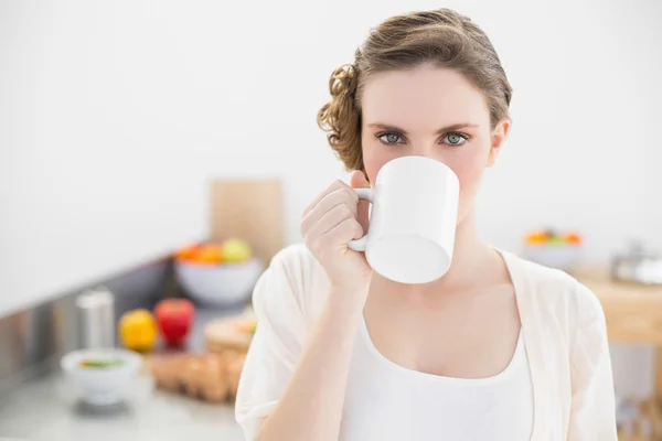 Schöne Frau trinkt aus Tasse, die in ihrer Küche steht — Stockfoto