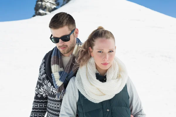 Couple in warm clothing in front of snowed hill — Stock Photo, Image