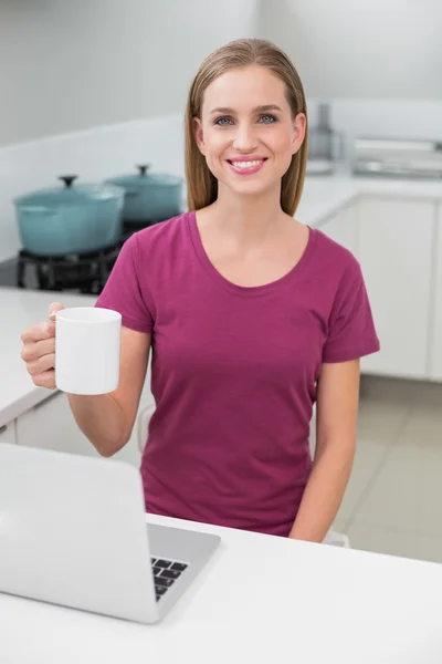 Rubia mujer casual usando portátil celebración taza — Foto de Stock