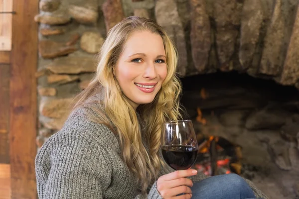 Hermosa mujer con vino en frente de la chimenea encendida — Foto de Stock