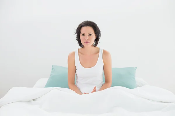 Ritratto di una donna seria seduta a letto — Foto Stock