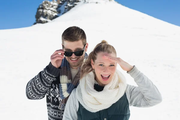 Happy couple in warm clothing in front of snowed hill — Stock Photo, Image