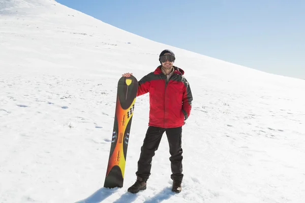 Усміхнений чоловік з лижною дошкою стоїть на снігу — стокове фото