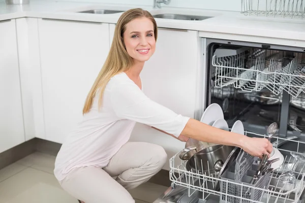 Sonriendo hermosa modelo arrodillado junto a lavavajillas — Foto de Stock