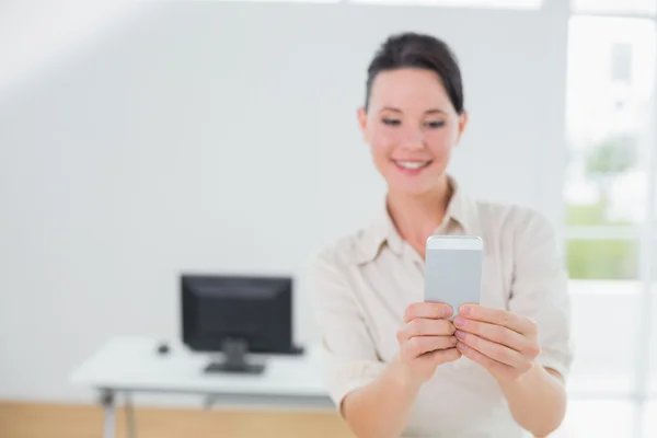 Geschäftsfrau schaut im Büro auf Handy — Stockfoto