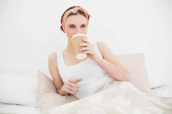 Mujer bebiendo un café acostada en su cama — Foto de Stock