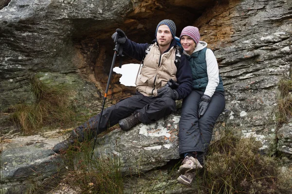 Pareja sonriente en el rock durante una caminata — Foto de Stock