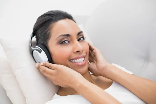 Zawartość kobieta relaksujące słuchanie muzyki, leżąc na kanapie — Zdjęcie stockowe