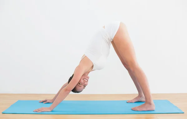 Side view of a smiling woman exercising on mat — Stock Photo, Image