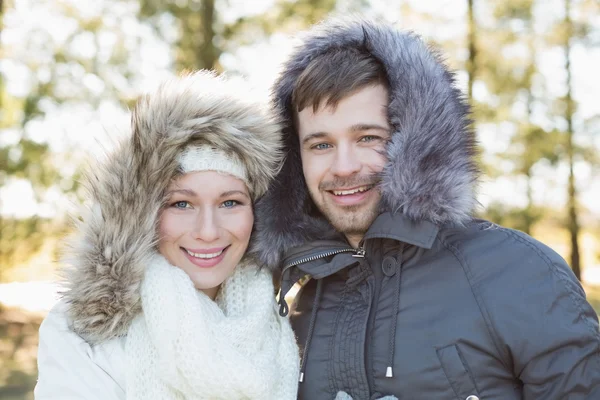 Couple souriant en fourrure capuche vestes dans les bois — Photo