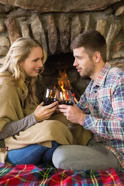 Couple toasting wineglasses in front of lit fireplace — Stock Photo, Image