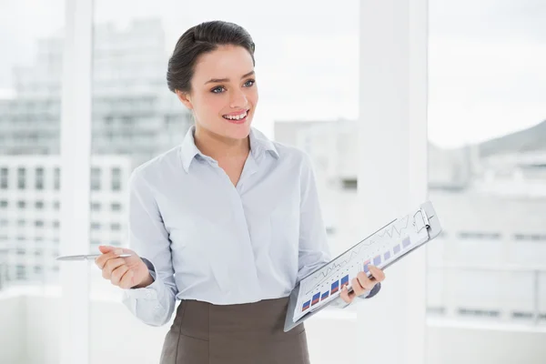 Smiling businesswoman with graphs in office — Stock Photo, Image