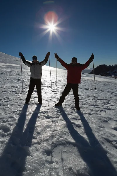 Silhouette coppia alzando le mani con bastoni da sci sulla neve — Foto Stock