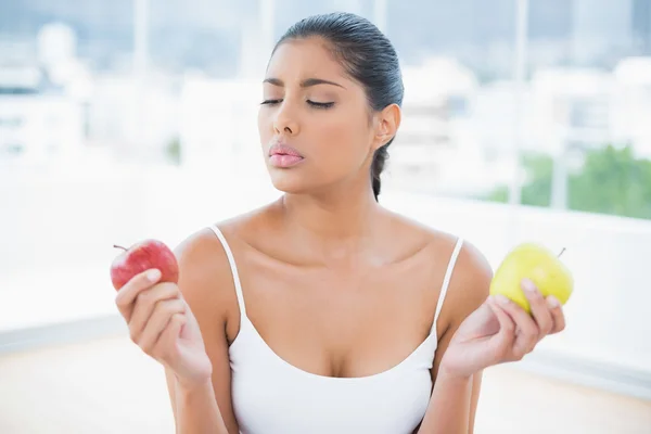 Serious toned brunette holding apples — Stock Photo, Image