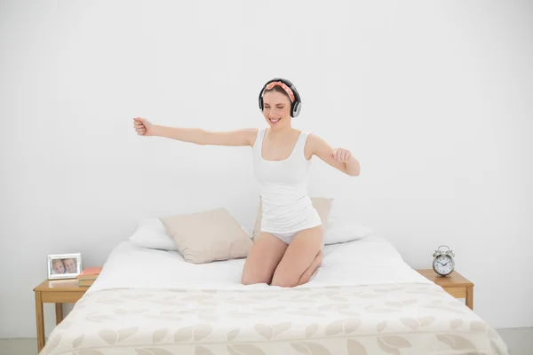 Mujer bonita moviéndose en su cama mientras escucha música — Foto de Stock