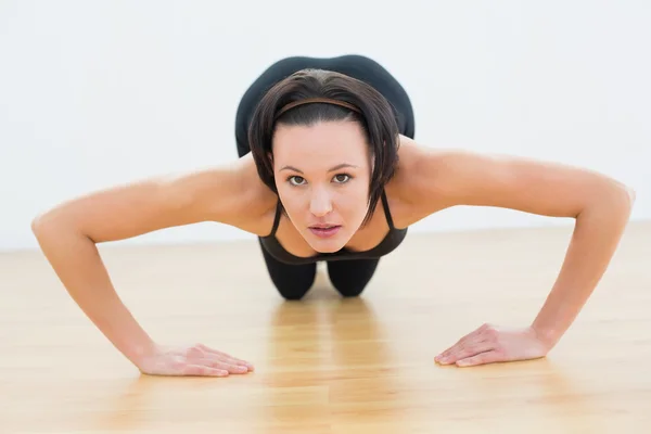 Ustalona piękna kobieta robi push up w fitness studio — Zdjęcie stockowe