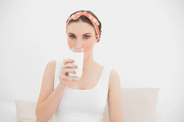 Woman drinking a glass of milk looking into the camera — Stock Photo, Image