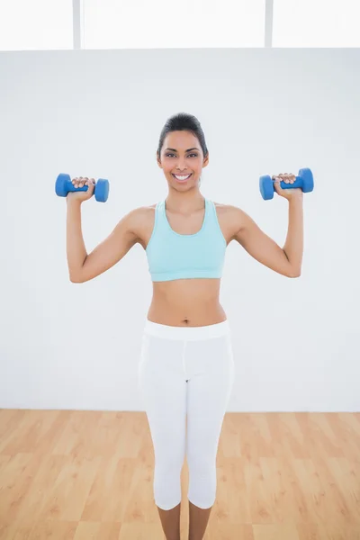 Attractive slim woman lifting blue dumbbells — Stock Photo, Image