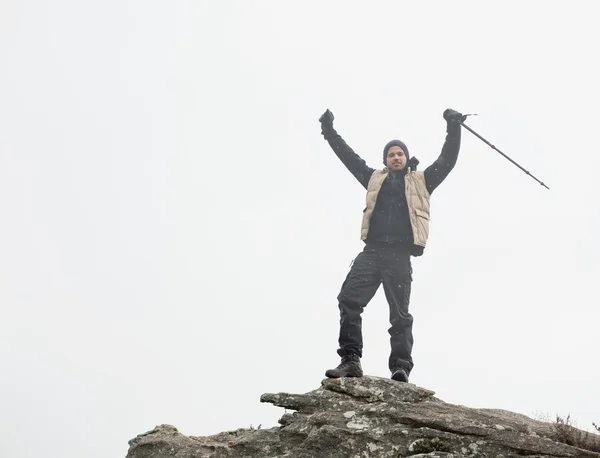 L'uomo con le mani alzate sulla roccia contro il cielo — Foto Stock