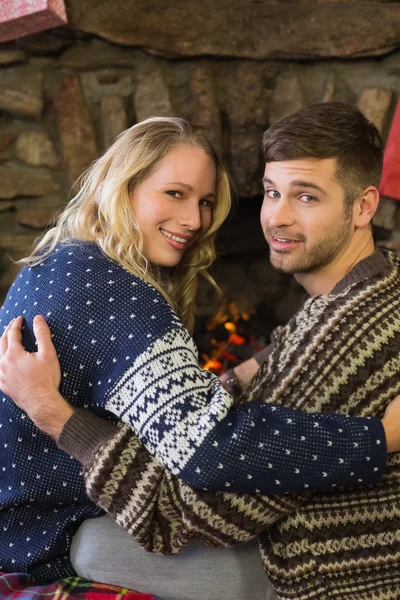 Couple smiling in front of fireplace — Stock Photo, Image