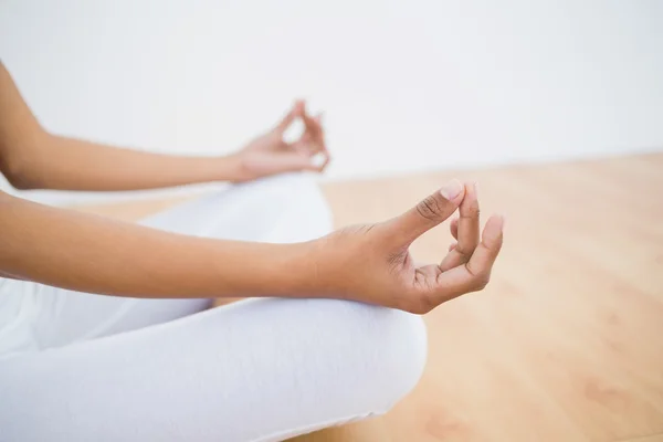 Mid section of slim young woman meditating sitting in lotus position in fitness hall — ストック写真