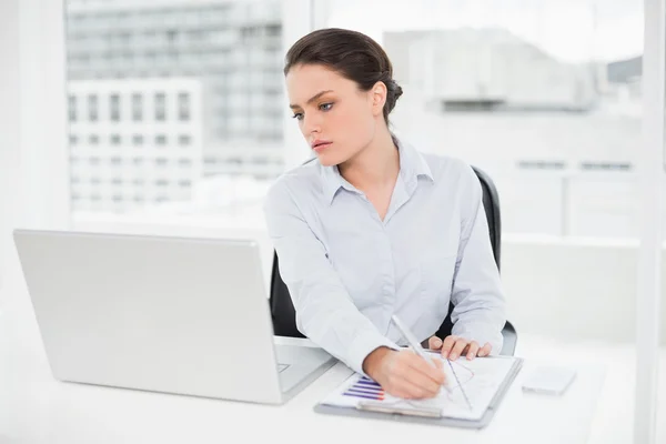 Empresaria con gráficos y laptop en oficina —  Fotos de Stock