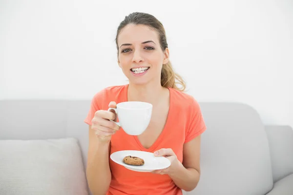 Atractiva morena sosteniendo una taza sonriendo alegremente a la cámara —  Fotos de Stock