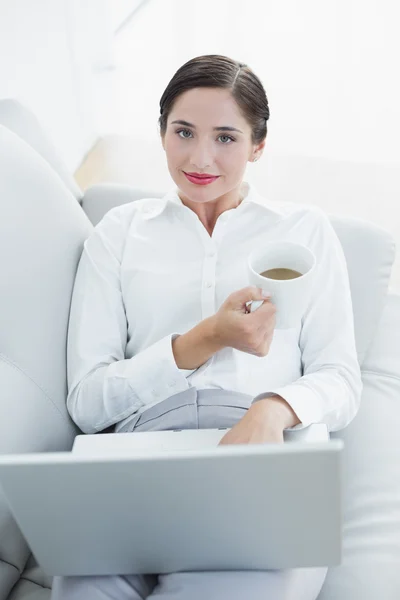 Mujer bien vestida con portátil y taza de café en el sofá — Foto de Stock