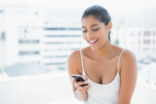 Fröhlich getönte Brünette mit Handy — Stockfoto