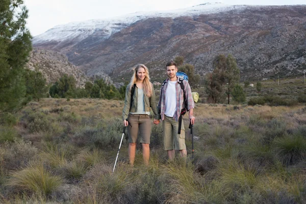 Koppel met rugzakken en trekking Polen tegen de berg — Stockfoto